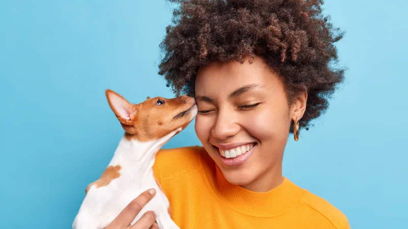 Photo of a dog giving a woman kisses